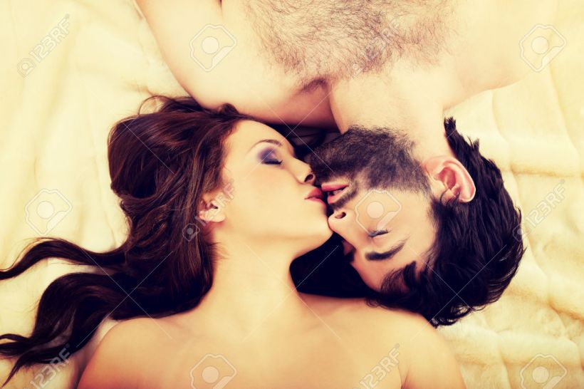 Relaxed young couple kissing in bed.